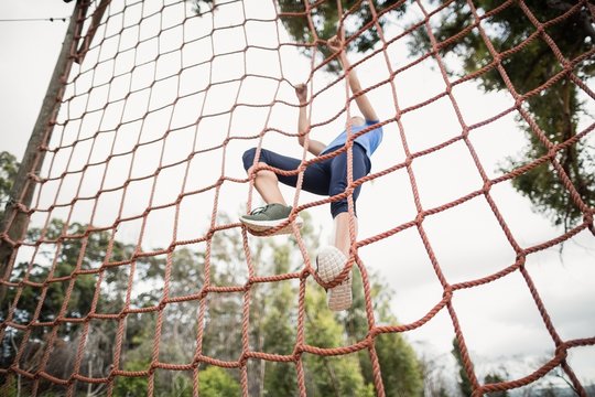 Woman climbing a net during obstacle course