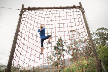 Woman climbing a net during obstacle course