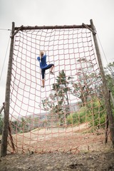 Woman climbing a net during obstacle course