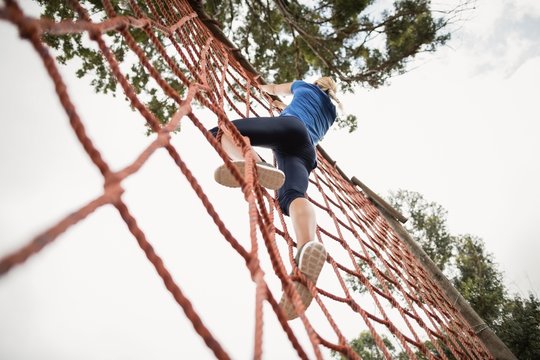 Woman climbing a net during obstacle course