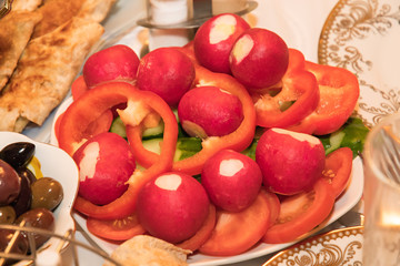 A plate of radish, red pepper chopped rings and cucumber
