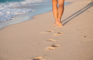 Closeup of a man's bare feet walking at a beach at sunset,