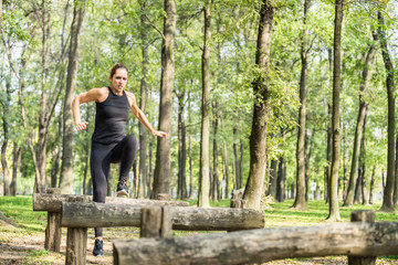 Female athlete jumping across wooden barriers