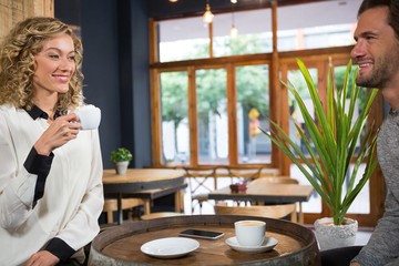 Couple talking while having coffee at table in cafe