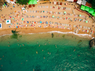 Top View of Beach. Aerial view of sandy beach with tourists swimming in beautiful clear sea water. People on the beach.