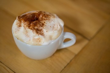 Coffee cup with creamy froth on table in cafe