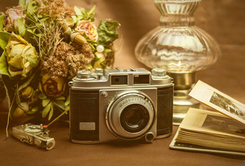 Alte Kamera mit Fotoalbum, Blumen und Kerzenlicht 