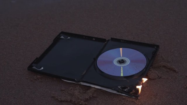 data cd dvd disc case in fire on the sand at coast HD