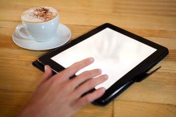 Hand using digital tablet with blank screen by coffee cup