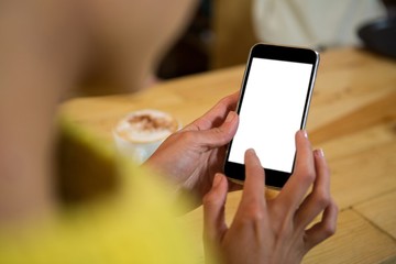 Woman using mobile phone at table in coffee shop