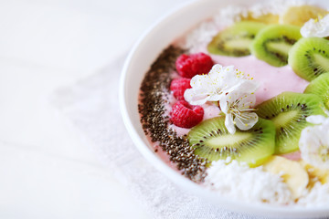 Raspberry and banana smoothie bowl with kiwi slices, shredded coconut and chia seeds.