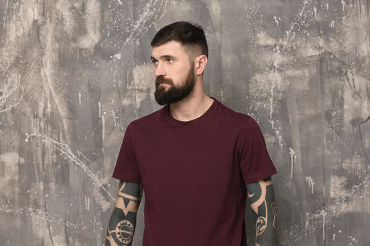 Handsome tattooed young man on gray background