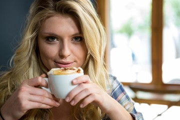 Beautiful young woman having coffee in cafe