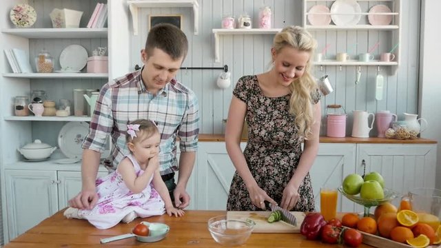 happy young family cooking in kitchen at home, vegetables salad and fruits, healthy breakfast