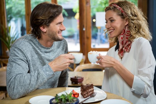 Smiling couple having coffee at table in cafeteria