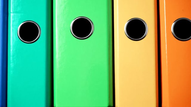 Close up of many colorful file folders, ring binders as vivid color office background. Dolly slider shot 4K ProRes HQ codec
