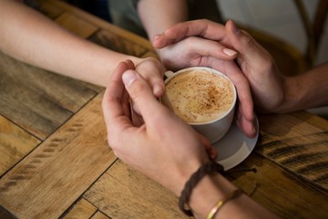 Couple holding hands and coffee cup in cafeteria