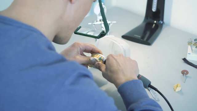 Closeup of grinding teeth crowns with instruments in dental lab in 4K