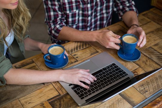 Couple using laptop while having coffee in cafeteria