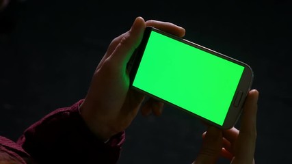 Teenager girl holding smart phone in hands indoor in the dark