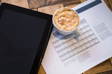 Digital tablet with coffee and document on table