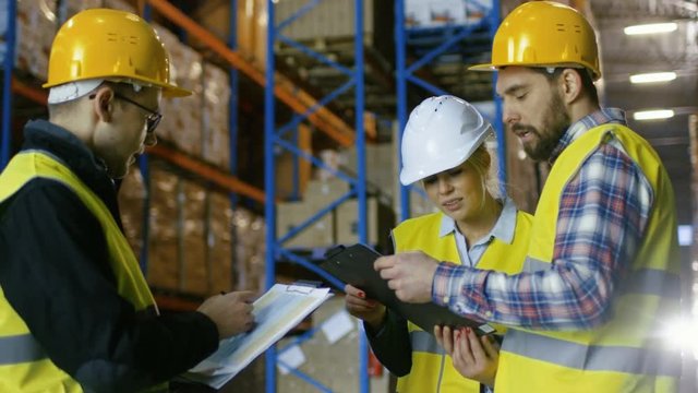 Team of Male and Female Inspectors/ Workers/Auditors Have Discussion in Big Warehouse with Rows of Racks with Pallets. Shot on RED EPIC-W 8K Helium Cinema Camera.