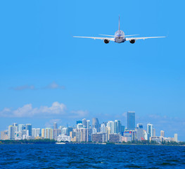 Miami, Florida, skyline viewed from Biscayne Bay with a commercial passenger jet airliner plane flying arriving or departing the International Airport. - 144010622