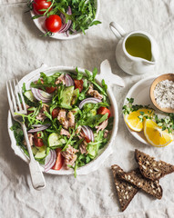 Tuna, arugula, tomato, cucumber salad with mustard dressing. Healthy diet food. Mediterranean style. On a light background, top view
