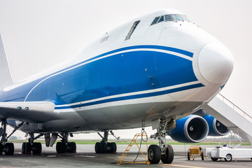 Close-up of big cargo wide body aircraft with opened door and boarding ramp - obrazy, fototapety, plakaty