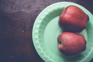 top view of two apples on green plate on wooden table