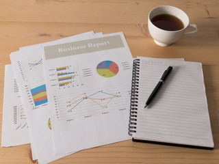Business workplace with coffee and papers with graphs and diagrams. Business work concept.