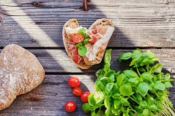 Healthy brown bread with ham, cheese and tomatoes on a wooden table.