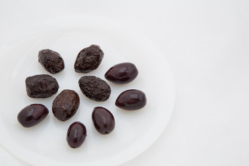  few dark black olives on a white plate and three green spikes on a white mesh background with an empty place for the inscription