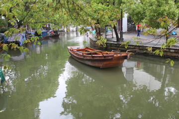 Fototapeta premium Boat Boats Canal Canals China Chinese Water Town Watertown Green Leaves Leaf Tree Trees Wooden Brown Wood Zhouzhuang Zhou Zhuang Jiangsu Asia Asian Reflection Reflect