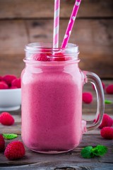 Raspberry smoothie in mason jar on rustic wooden background