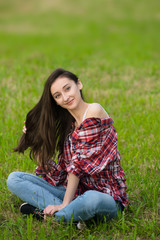 woman in jeans and shirt resting. Lays on the fresh grass