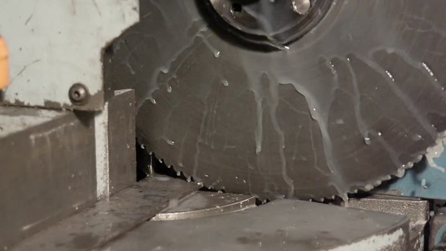 buzzsaw is sawing metal with floating water in slowmotion
