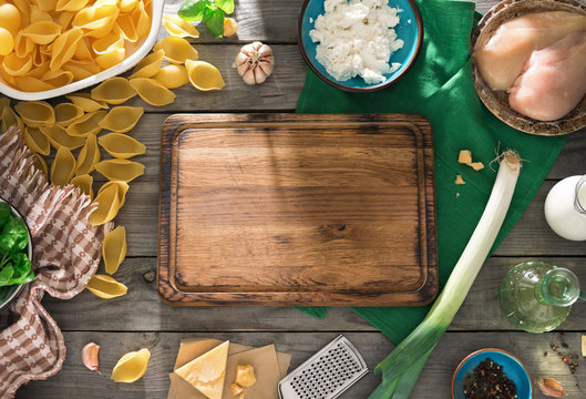 Empty kitchen board with ingredients for cooking delicious pasta