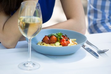 Cropped image of couple with food and wineglass on table