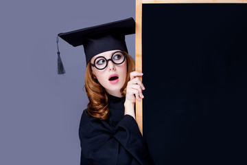 photo of beautiful young alumnus with blackboard on the wonderful grey studio background