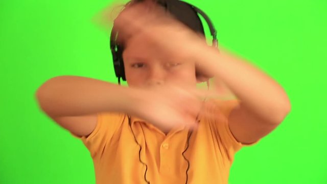 Happy young boy with headphones listening to music and dancing against chroma key green screen background Time Lapse