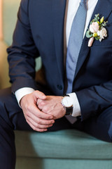 groom in black suit with expensive watches sitting in the chair close-up of hands