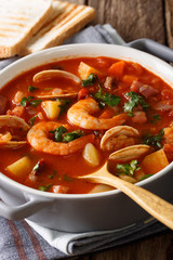 Manhattan clam chowder soup with shellfish and bacon close-up on a in a pan. Vertical