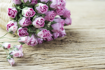 Pink paper rose in weave basket on old wood