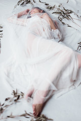 girl with a beautiful figure in white boudoir dress sitting near the chair, legs close-up