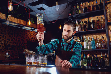 The barman pours alcohol into a glass. 