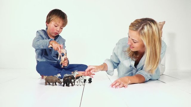 mutter und sohn spielen gemeinsam mit verschiednen plastiktieren