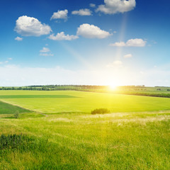 hilly terrain, spring field and sunrise on blue sky