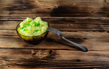 Mashed potatoes in glass bowl on wooden table