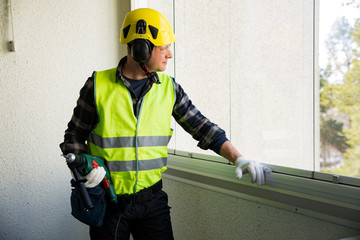 Male construction worker in hard hat with a drill. Building and renovation.